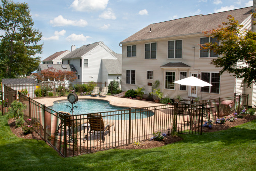 Lush backyard pool and patio behind colonial style home.